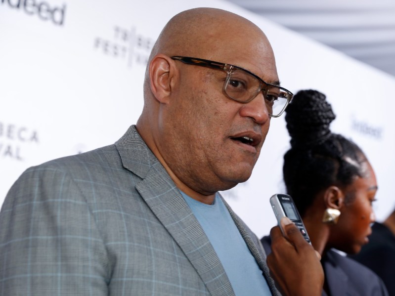 Laurence Fishburne wears a grey suit jacket as he answers questions on the red carpet