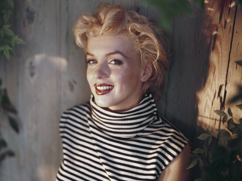 Marilyn Monroe smiles while wearing a black and white striped top