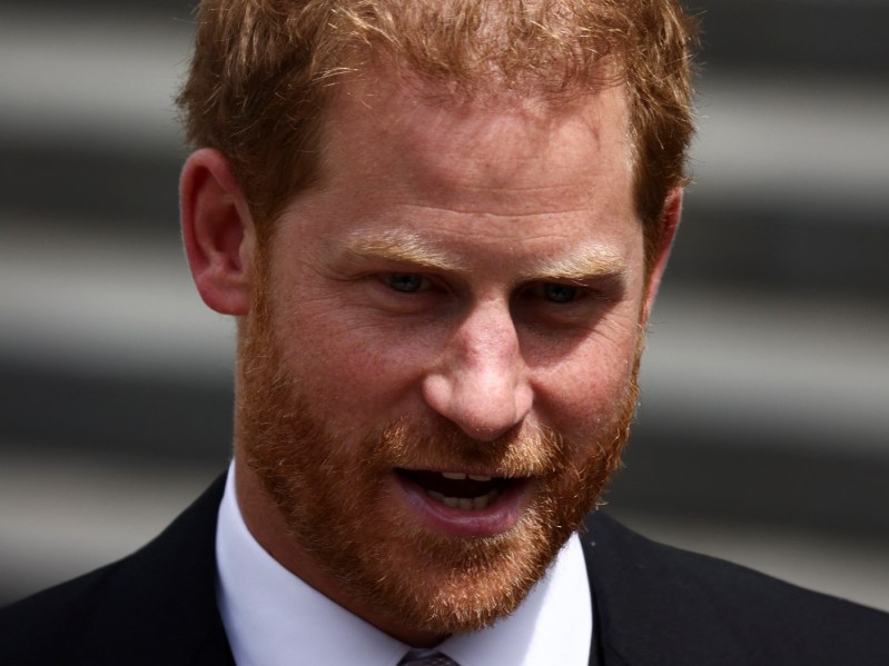 Prince Harry wears a dark suit as he walks down a flight of stairs outdoors at the Platinum Jubilee celebrations for Queen Elizabeth