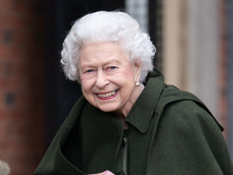 Queen Elizabeth smiles while wearing a green overcoat