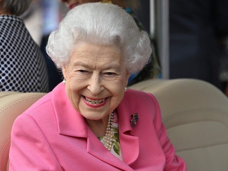 Queen Elizabeth smiling while wearing a pink suit