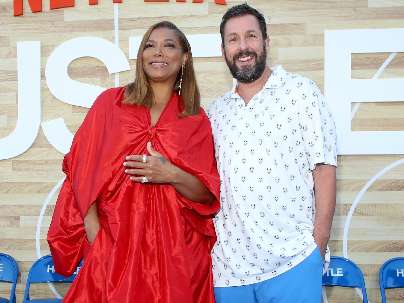 Queen Latifah (L) wearing red dress and Adam Sandler (R) wearing white button-down shirt
