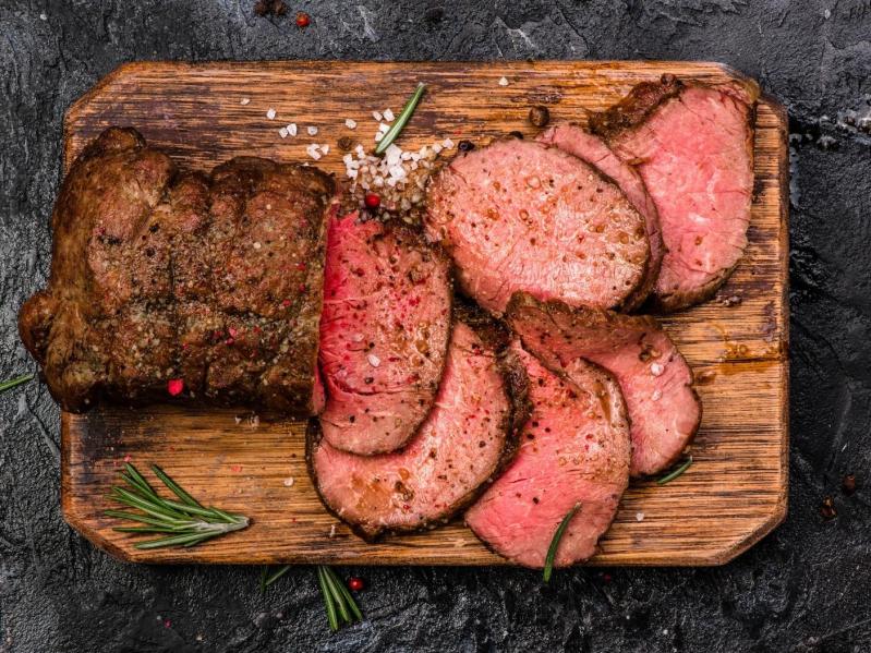 Roast beef on a cutting board with salt and pepper