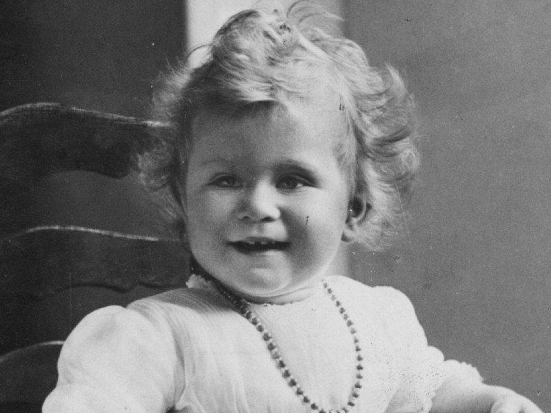 Queen Elizabeth sits in a chair for her first birthday portrait