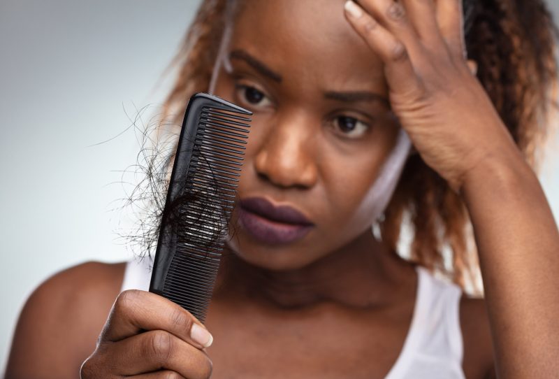Woman looking upset at amount of hair in a comb