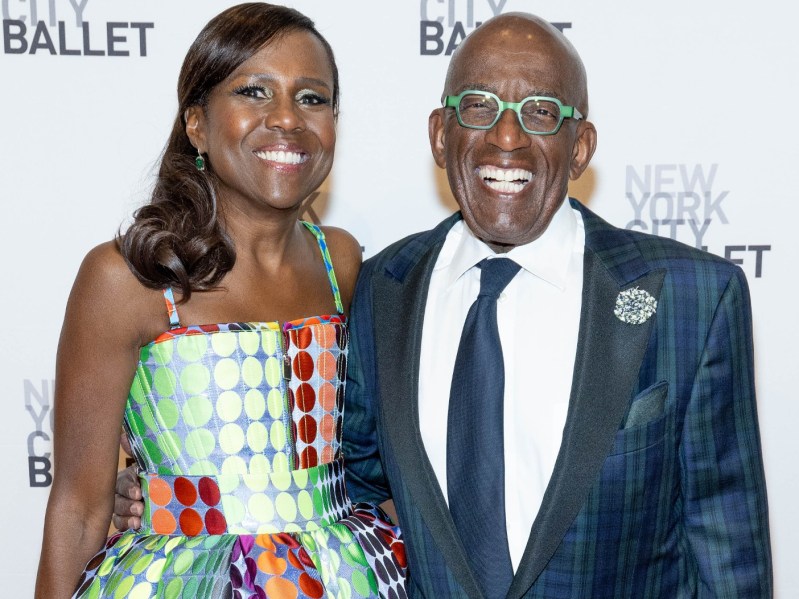 Al Roker (R) wearing navy suit and green glasses, standing and smiling next to Deborah Roberts, who is wearing a patterned dress