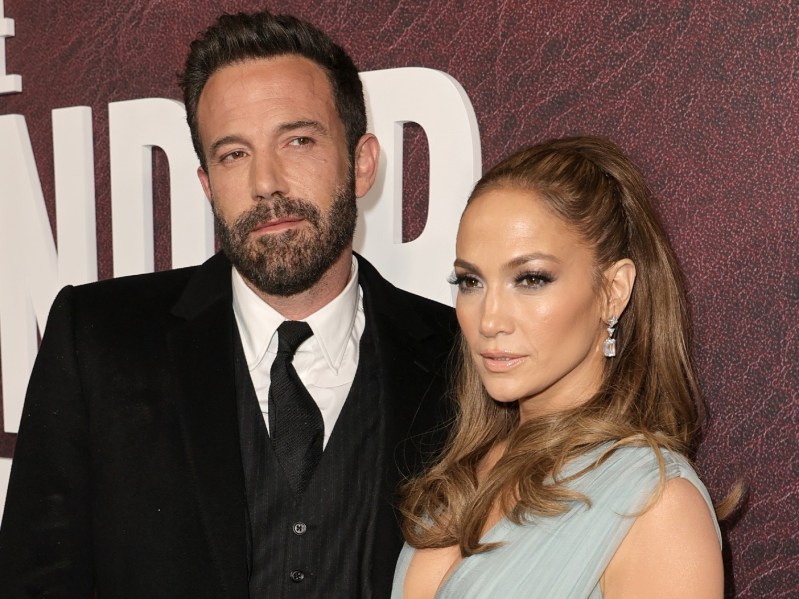 Ben Affleck (L) wearing classic suit and tie standing next to Jennifer Lopez, who is wearing a light blue dress