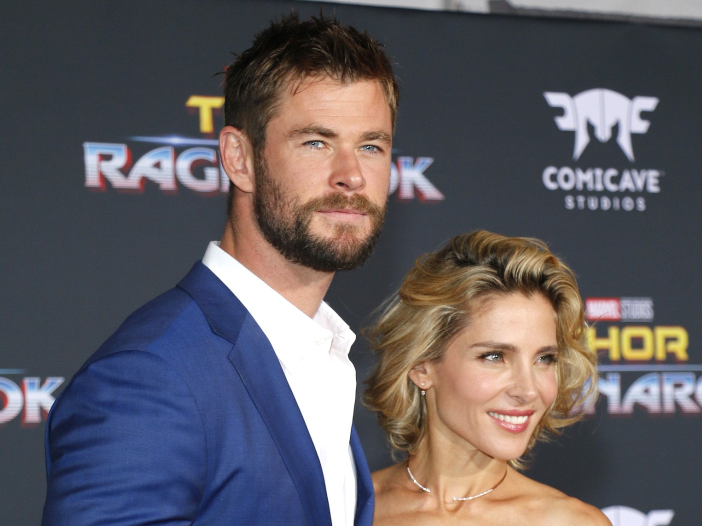Chris Hemsworth (L) wears dark blue blazer over white dress shirt, standing next for to Elsa Pataky, who can be seen from the shoulders up