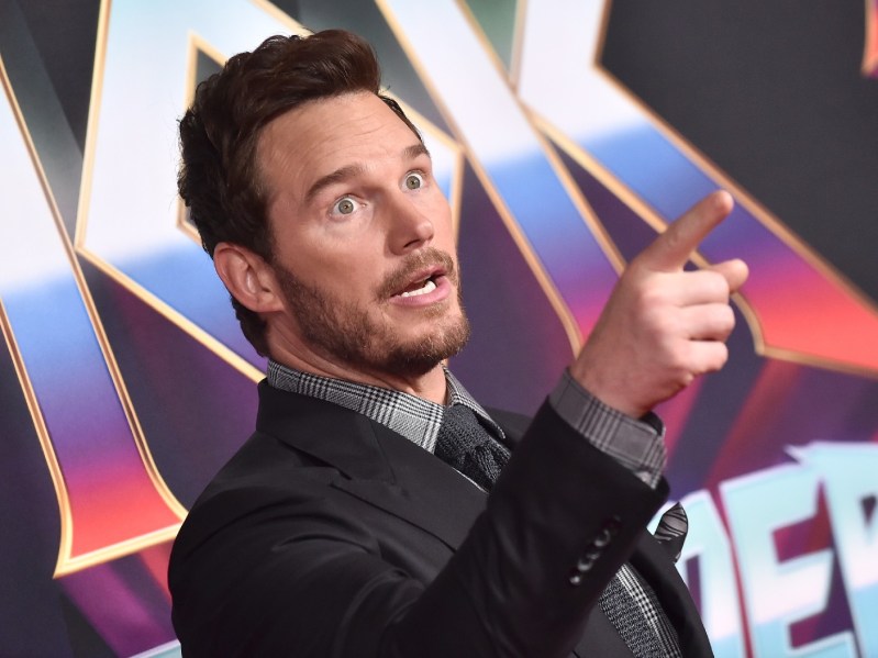 Chris Pratt wears a dark gray suit on the red carpet and points