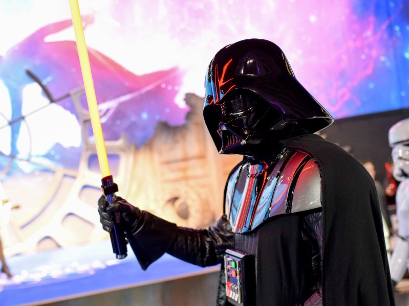 Darth Vader wields a yellow lightsaber against a colorful backdrop