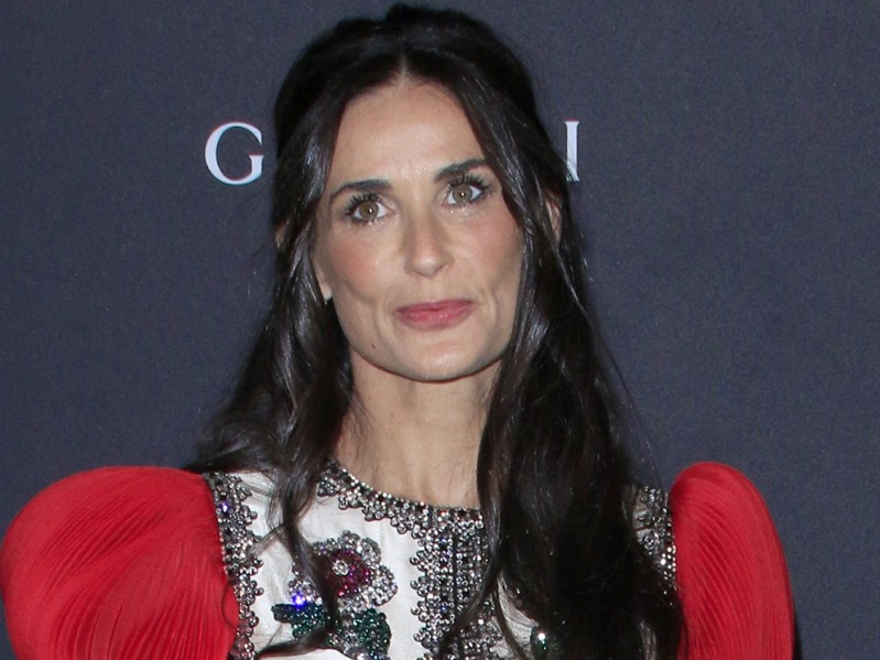 Demi Moore posing in white printed top with puffy red sleeves
