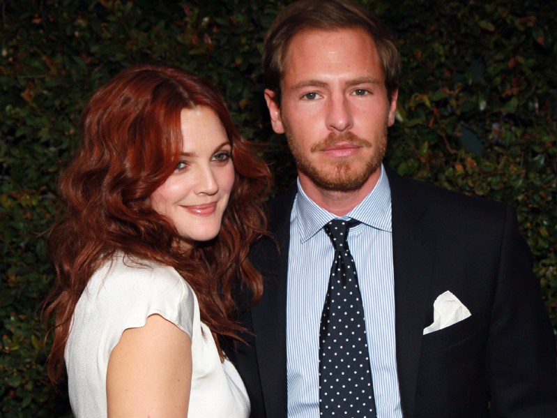 Drew Barrymore wears a white blouse and stands with now ex-husband Will Kopelman on the red carpet