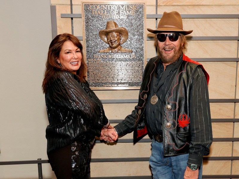 Mary Jane Thomas (L) shaking hands with Hank Williams Jr. in front of a plaque inducting him into the country music hall of fame