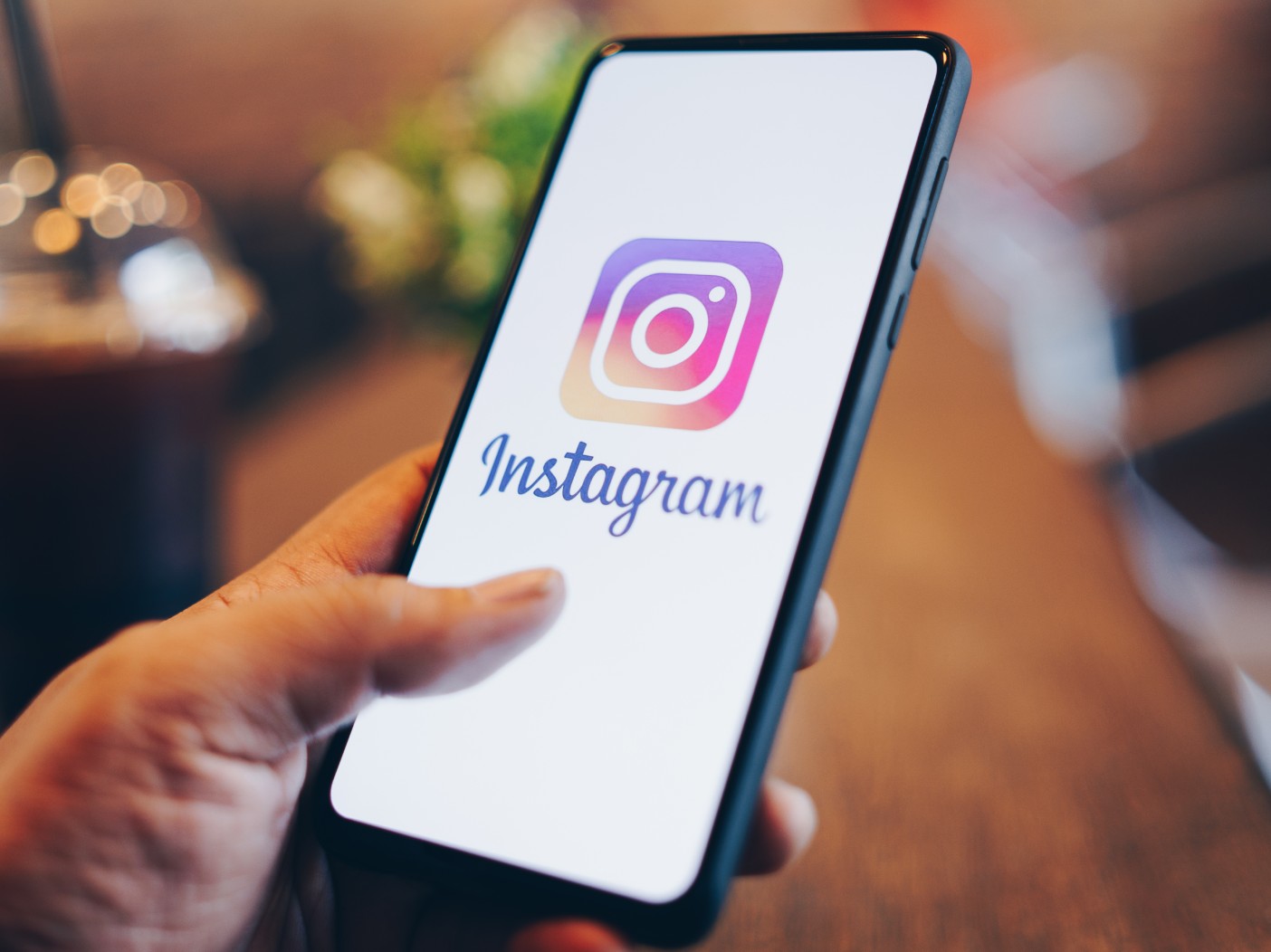 Hand holding smartphone, the screen of which is displaying the Instagram logo
