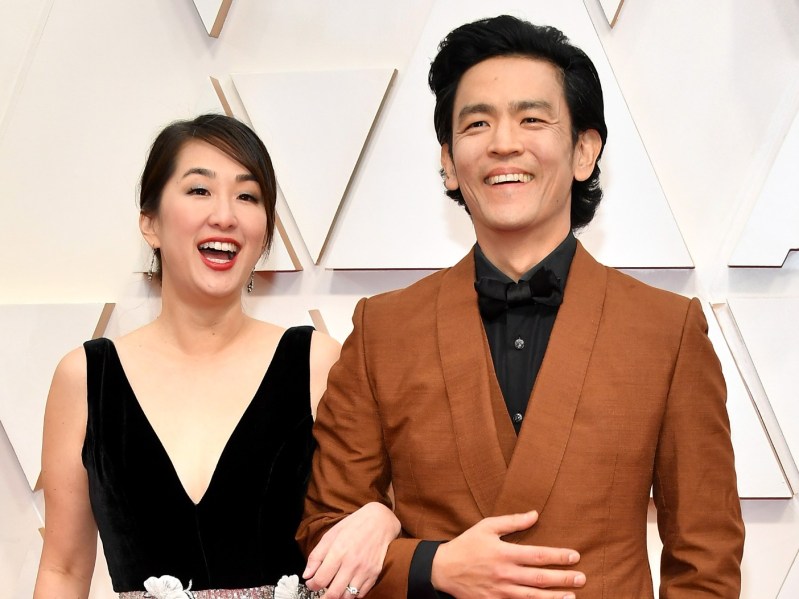 John Cho (R) in dark tan suit standing next to his wife Kerri, who is wearing a black gown