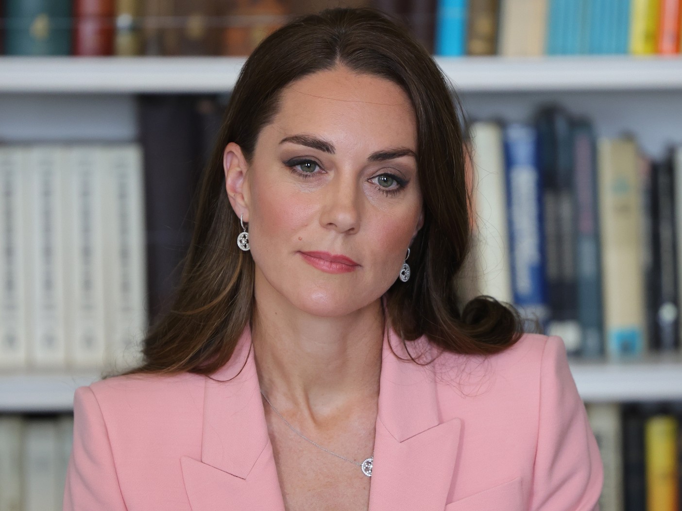 Kate Middleton looks somberly ahead while wearing light pink blazer