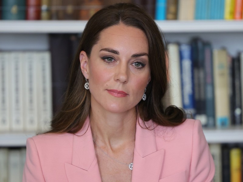 Kate Middleton looks somberly ahead while wearing light pink blazer