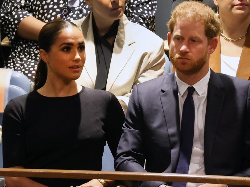 Meghan Markle, in a black dress, sits with Prince Harry, in a dark suit, in the UN