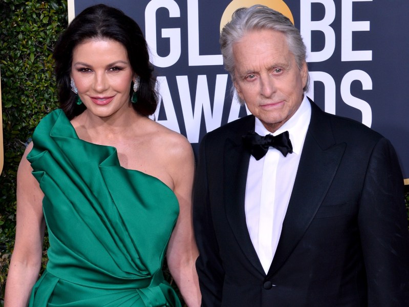 Catherine Zeta-Jones (L) in emerald green gown standing next to Michael Douglas, who is dressed in classic black suit and black bowtie