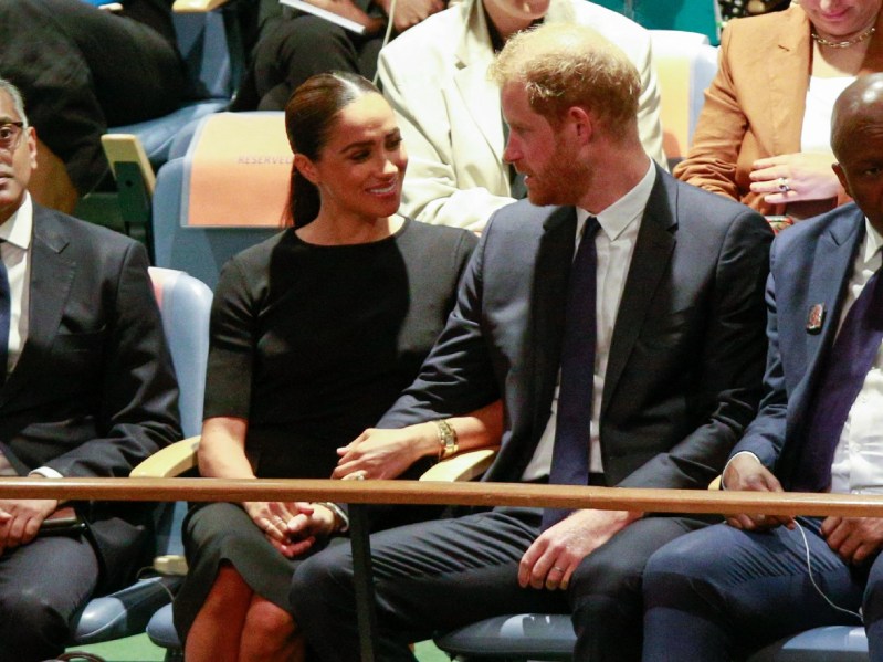 Meghan Markle, in a black dress, sits beside husband Prince Harry, in a dark suit, at the UN