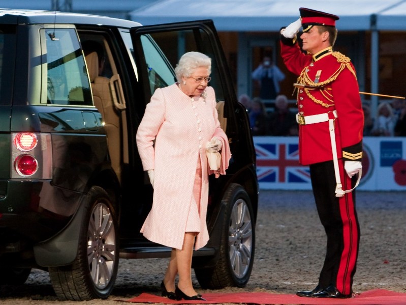 Queen Elizabeth wears a pink coat and dress as she exits a car