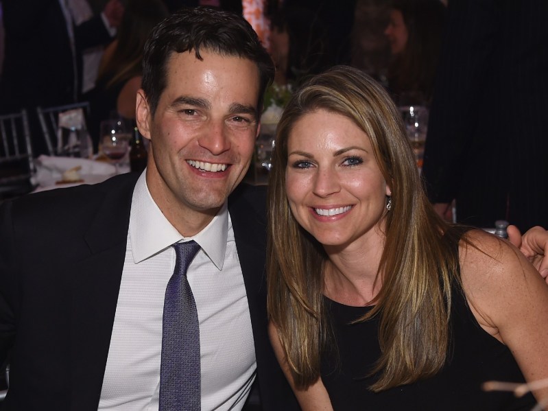 Rob Marciano (L) wearing black suit and tie, sitting next to Eryn Marciano, wearing a black dress