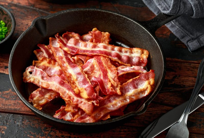 Crispy, cooked bacon in a cast iron skillet.