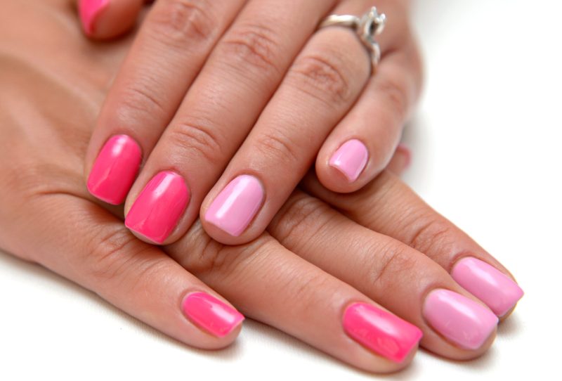 Crossed hands with a fresh manicure featuring multiple shades of pink.