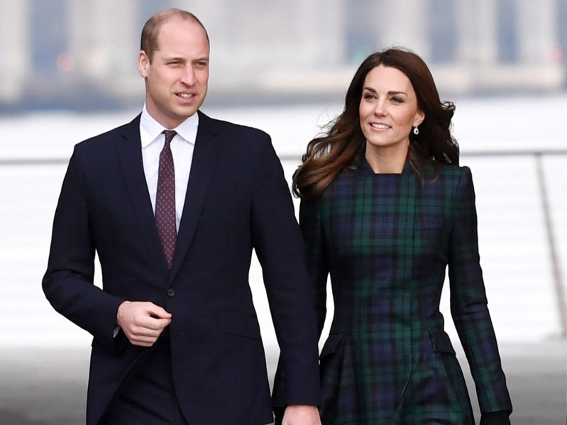 Kate Middleton (R) in blue and green plaid dress walking next to Prince William