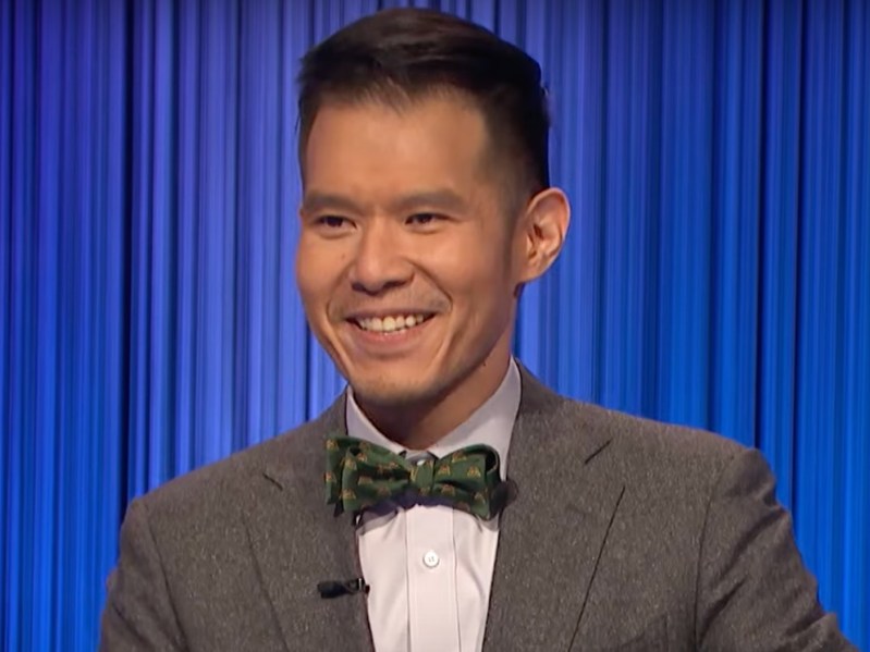 Contestant Yungsheng Wang smiles in gray suit with green bowtie
