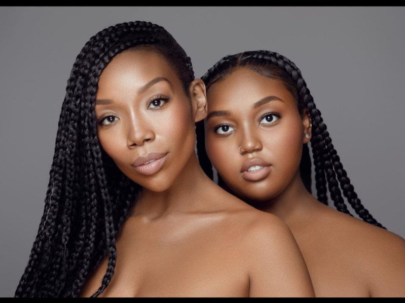 Brandy Norwood (L) posing with daughter against gray backdrop