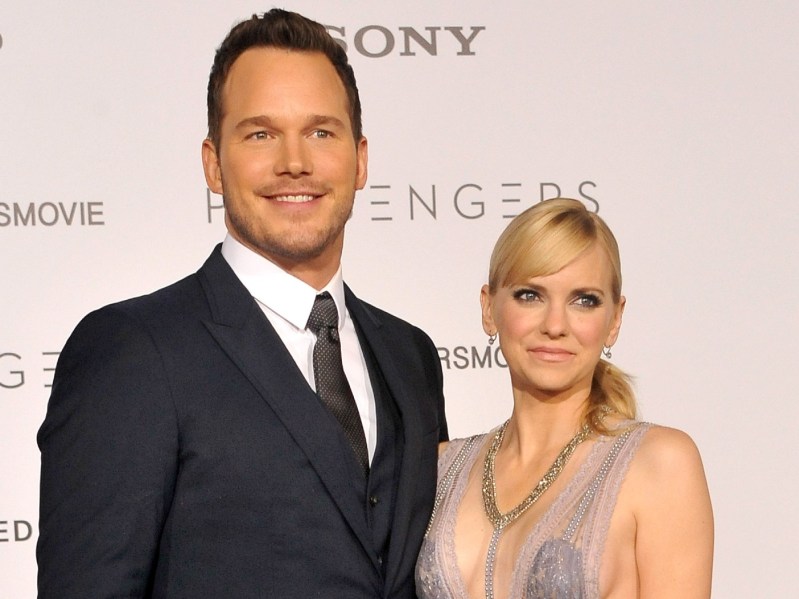 Chris Pratt (L) in classic suit and tie standing next to Anna Faris smiling against white backdrop