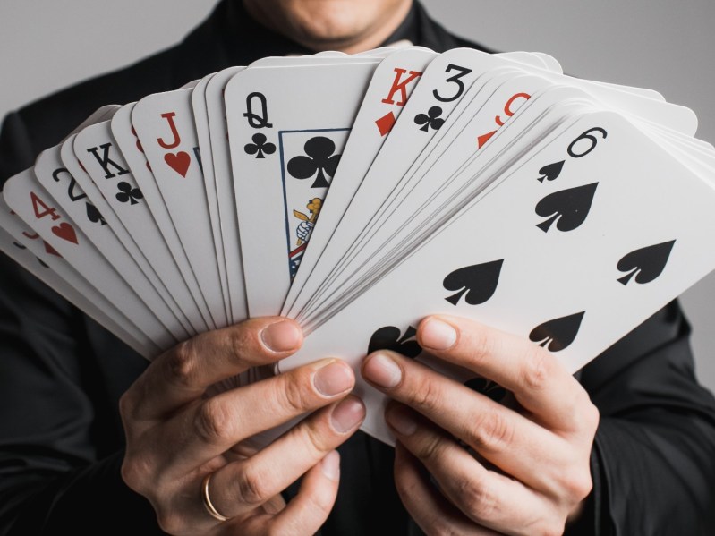 Closeup image of hands holding out a deck of cards, facing out
