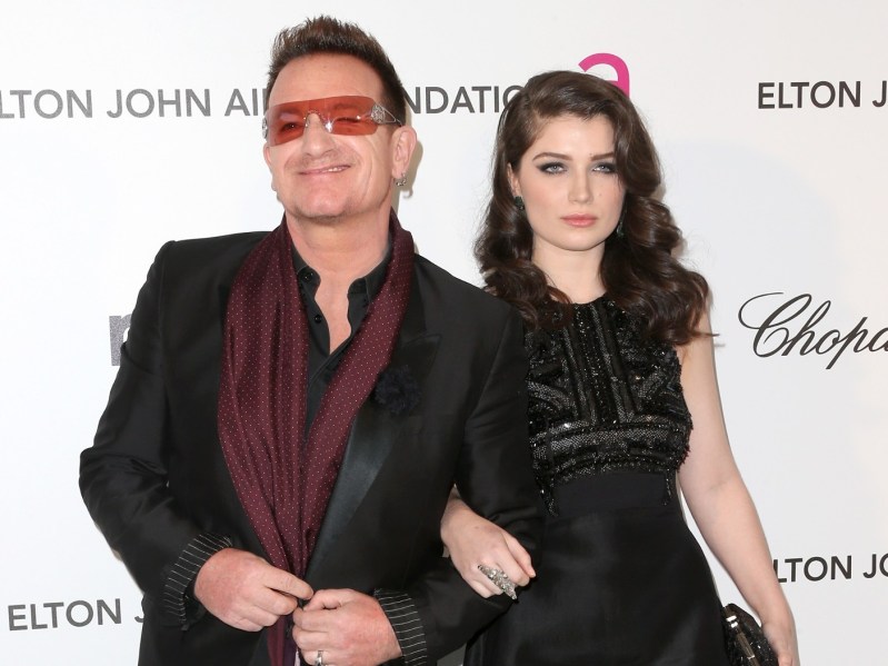Bono (L) in leather jacket standing next to Eve Hewson, who is wearing a black dress