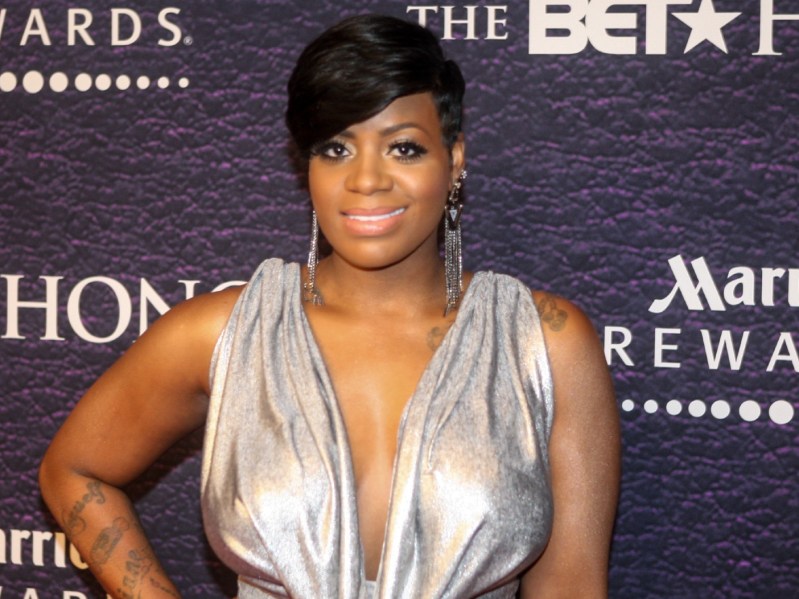 Fantasia smiles in silver gown against deep purple backdrop