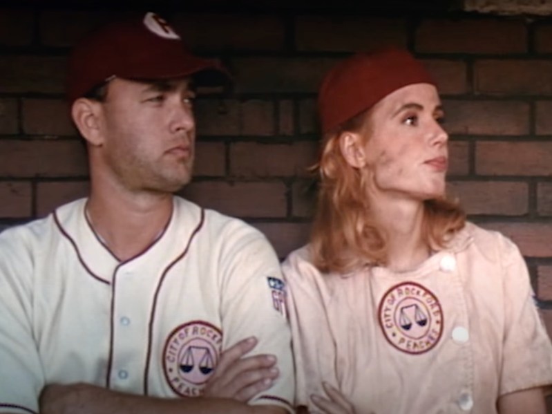 Tom Hanks (L) in baseball outfit sitting next to woman in baseball outfit