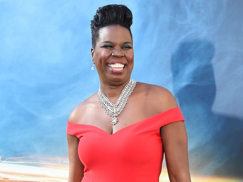 Leslie Jones smiles in red gown against blue backdrop