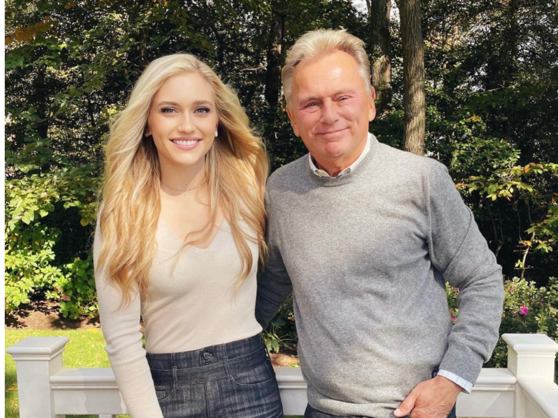 Maggie Sajak (L) in white top standing next to Pat Sajak, who is wearing a gray sweater