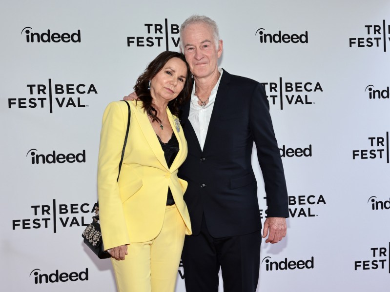 John McEnroe in a black suit with Patty Smyth in a yellow pantsuit