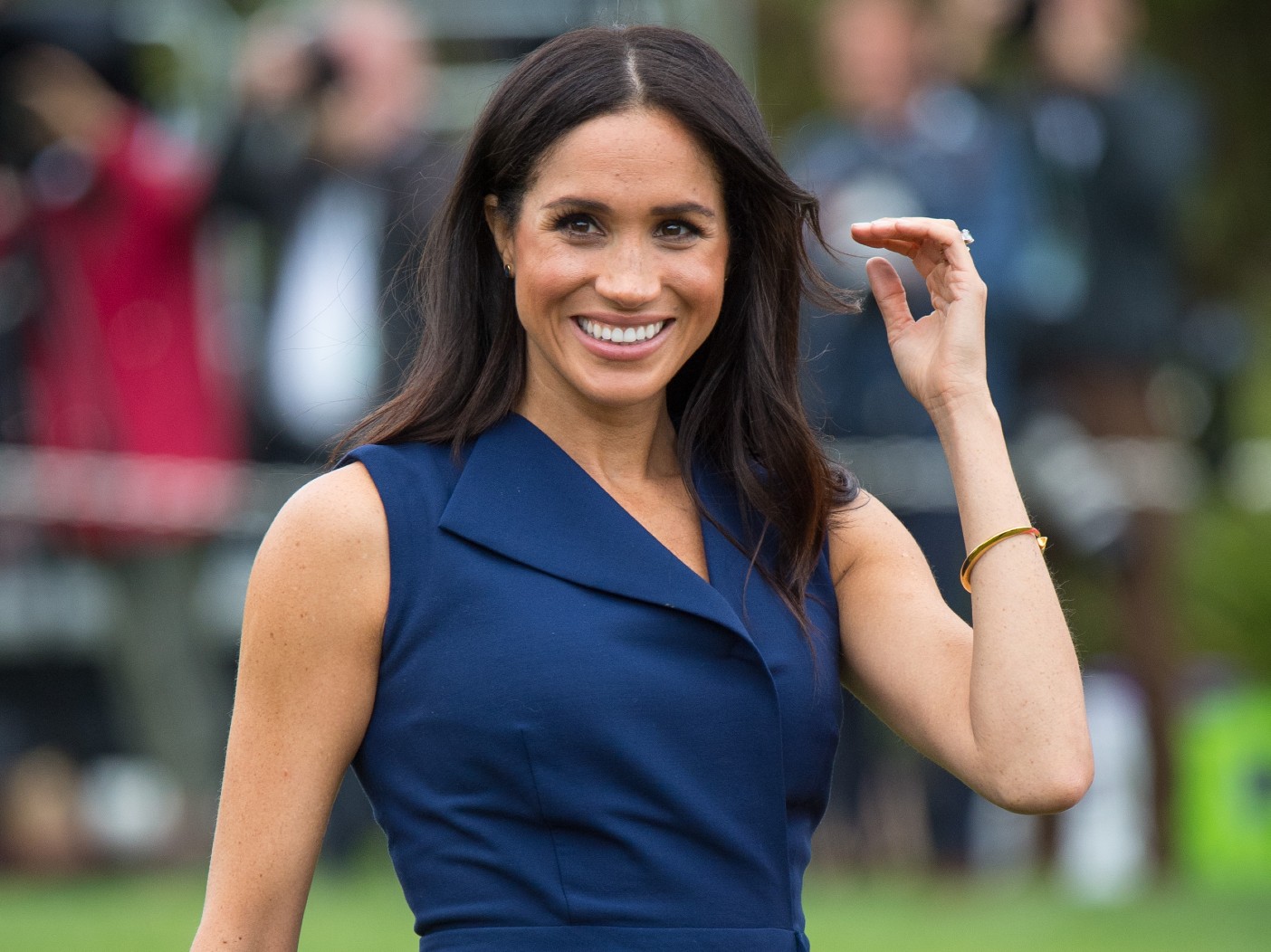 Meghan Markle smiles in navy blue dress outside