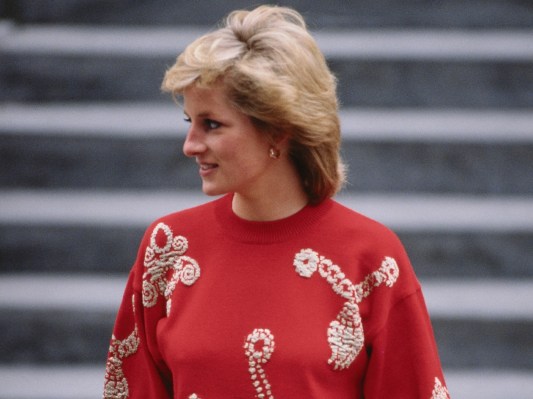 Princess Diana looks to her right in red sweater