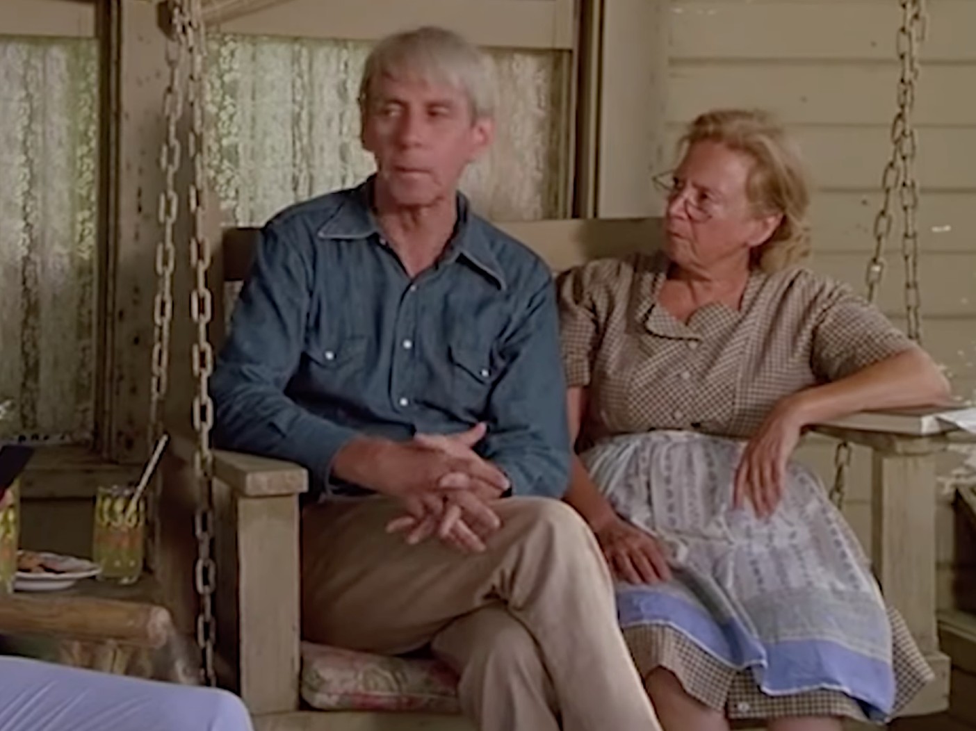 Actor Robert Sorrells sits in a chair next to a female actress in the movie "Fletch"