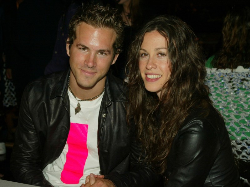 Ryan Reynolds (L) in white shirt with leather jacket sitting next to Alanis Morissette, who is wearing a black leather jacket