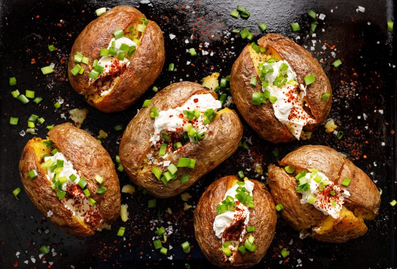 Top down view of baked potatoes covered with traditional toppings.