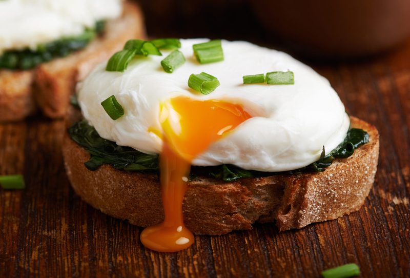 A poached egg topped with chives on toast