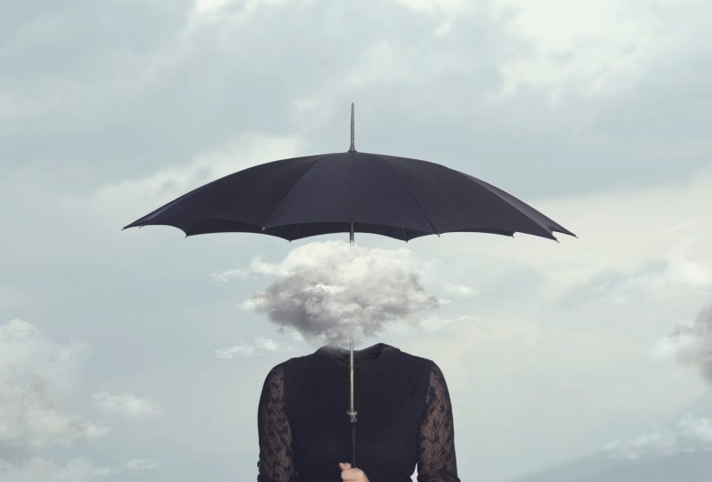 An image of a woman holding an umbrella with the head being replaced by a cloud.