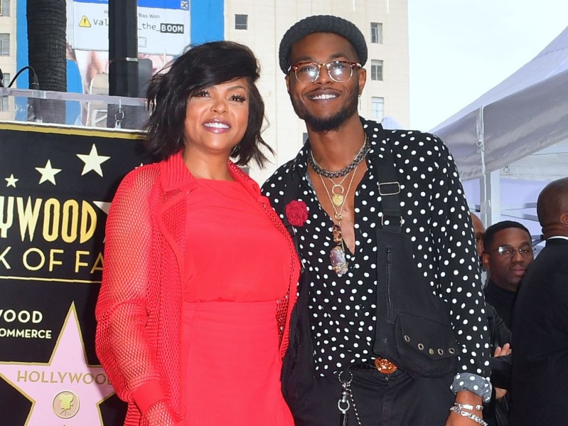 Taraji P. Henson (L) in red dress standing next to son, who is wearing a black shirt with white polka dots