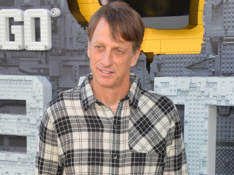 Tony Hawk smiling in black and white plaid button-down top