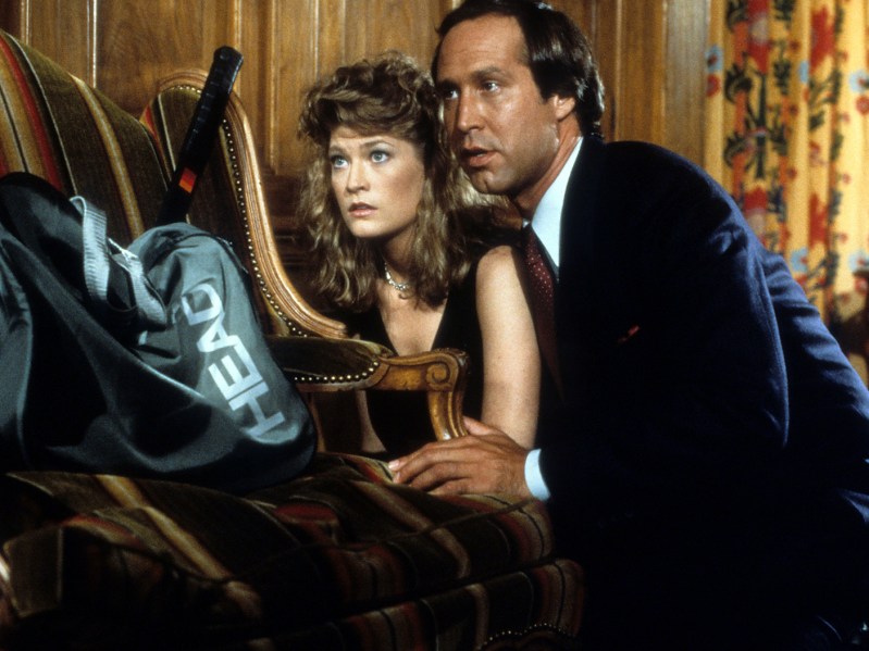 A scene from Fletch, with Dana Wheeler Nicolson hiding behind a couch with Chevy Chase