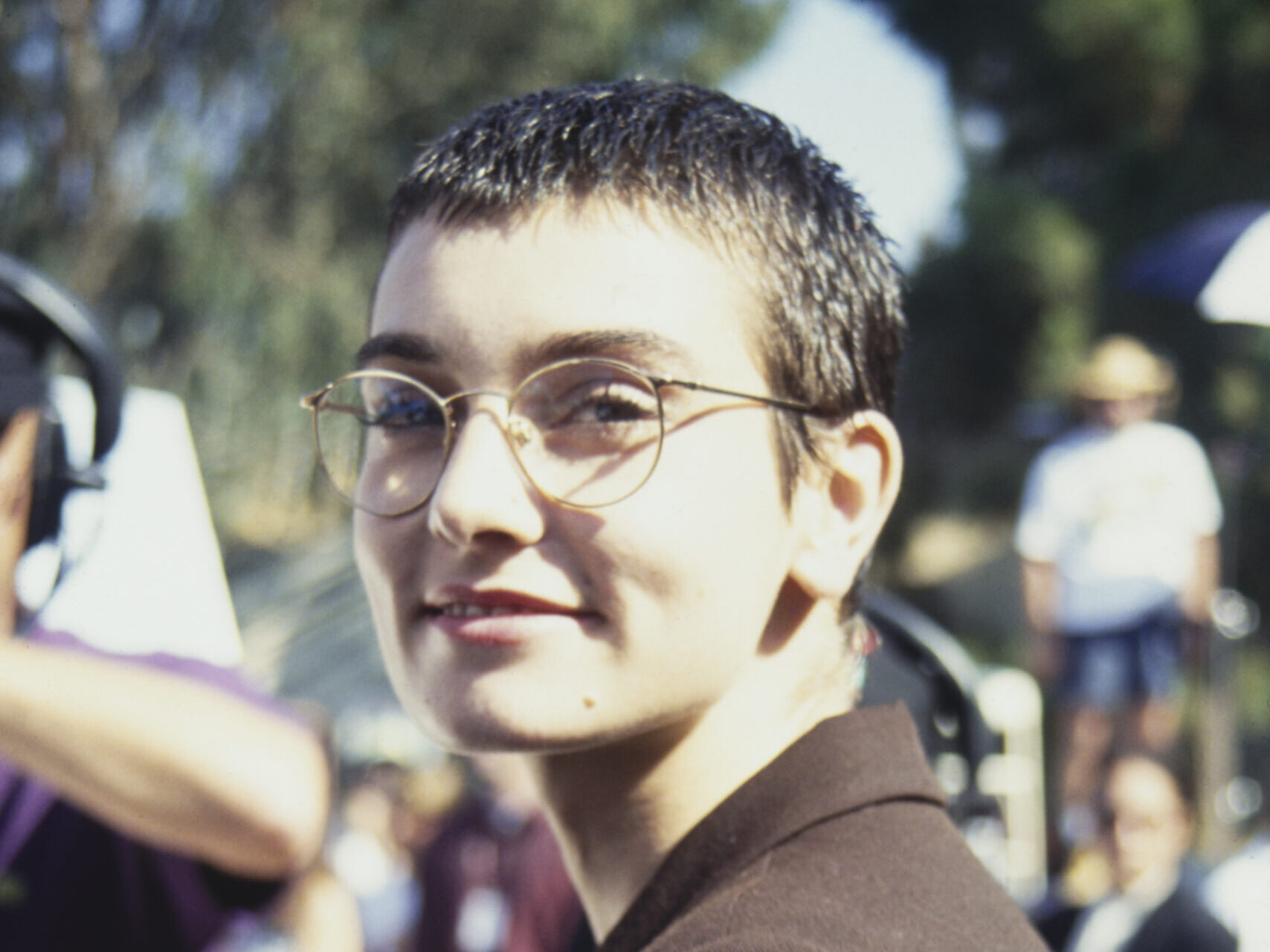 Sinead O'Connor in a brown suit and round glasses in 1993.
